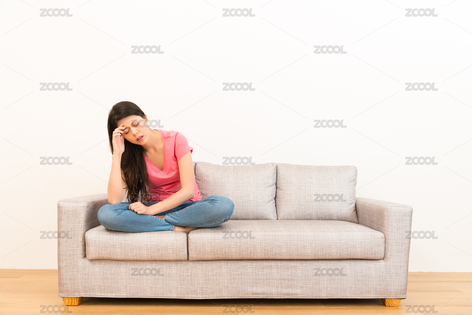 漂亮的女人坐在客厅的感觉在家里与白色背景COPYSPACE木地板在完成工作后剩下疲惫和头痛的沙发上。