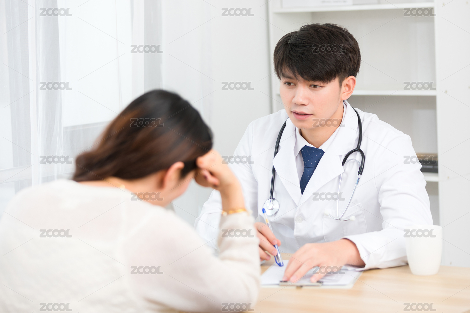 坐在办公室里的亚洲男医生正在询问患者的病情