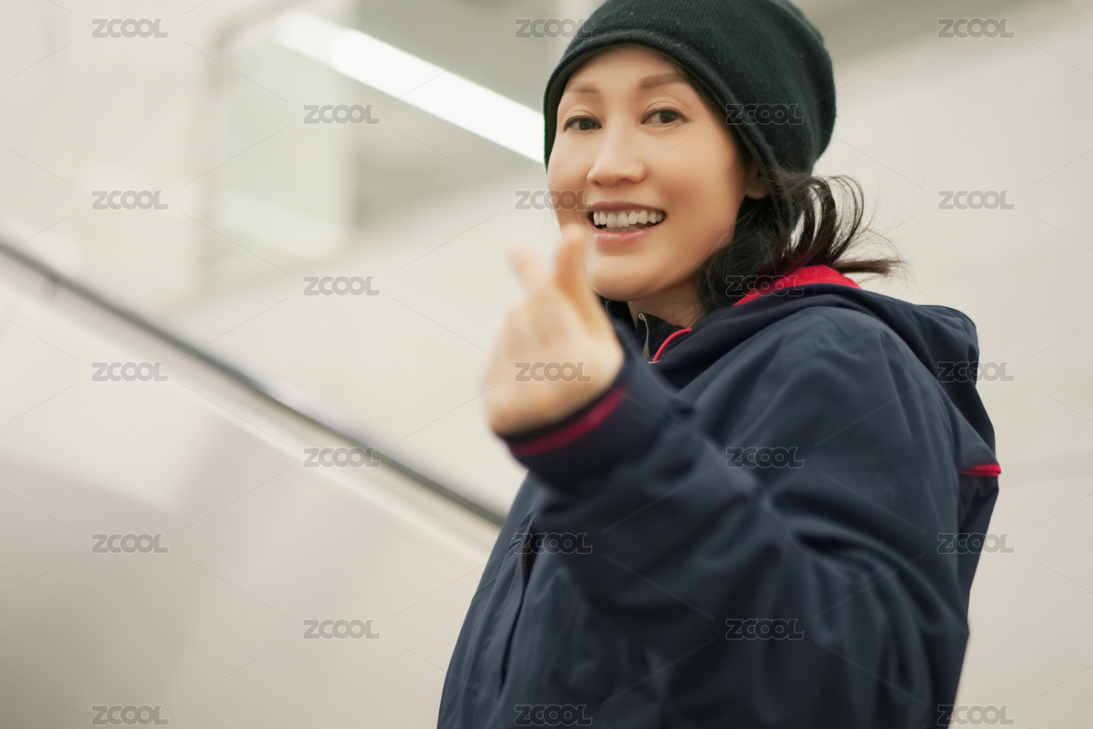 微笑的女人在乘坐自动扶梯时竖起比心手势（主预览-9002453） - 未分类 - 站酷设计师feichangbaoquan原创素材 - 站酷ZCOOL