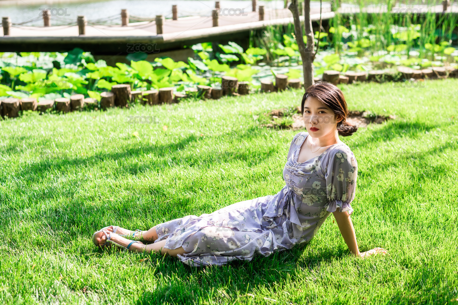 美丽优雅的亚洲女性坐在草地上，夏日午后的花园里，中国古典花园