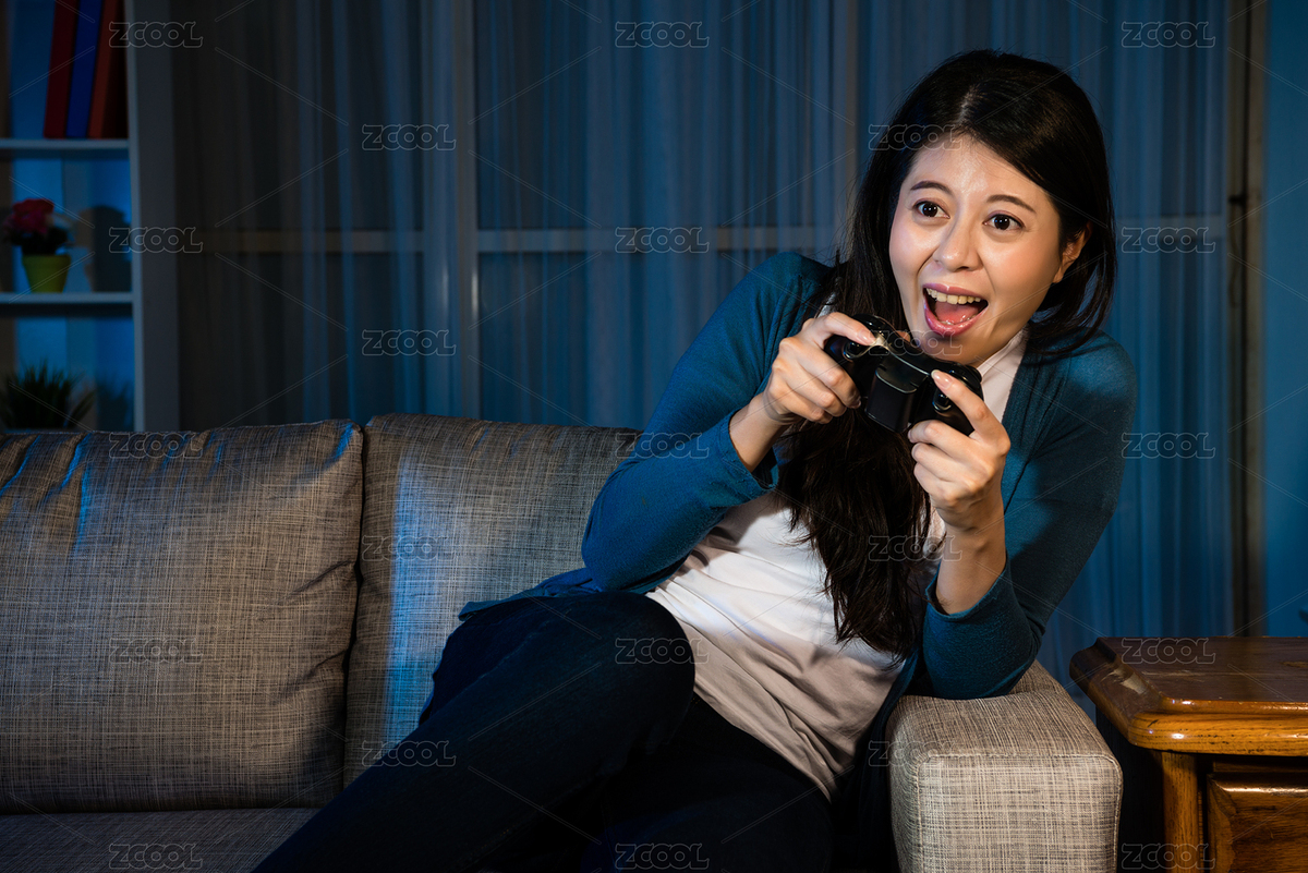 幸福的微笑小姐玩在線視頻游戲在晚上舉行的操縱桿控制移動(dòng)看著監(jiān)視器坐在客廳的沙發(fā)上。（主預(yù)覽-2261221） - 未分類 - 站酷設(shè)計(jì)師PRImageFactory原創(chuàng)素材 - 站酷ZCOOL