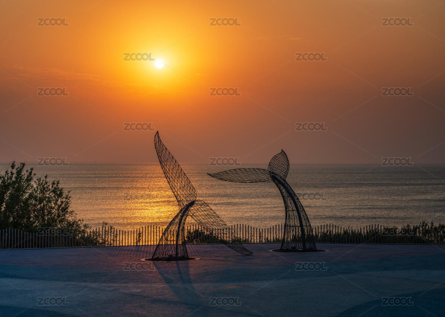 夕阳下唯美金色海平面与鲸鱼尾雕塑