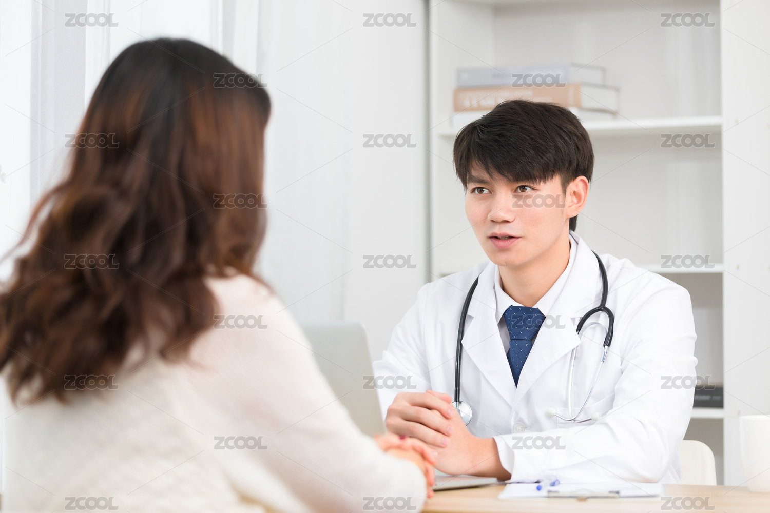坐在办公室里的亚洲男医生正在询问患者的病情