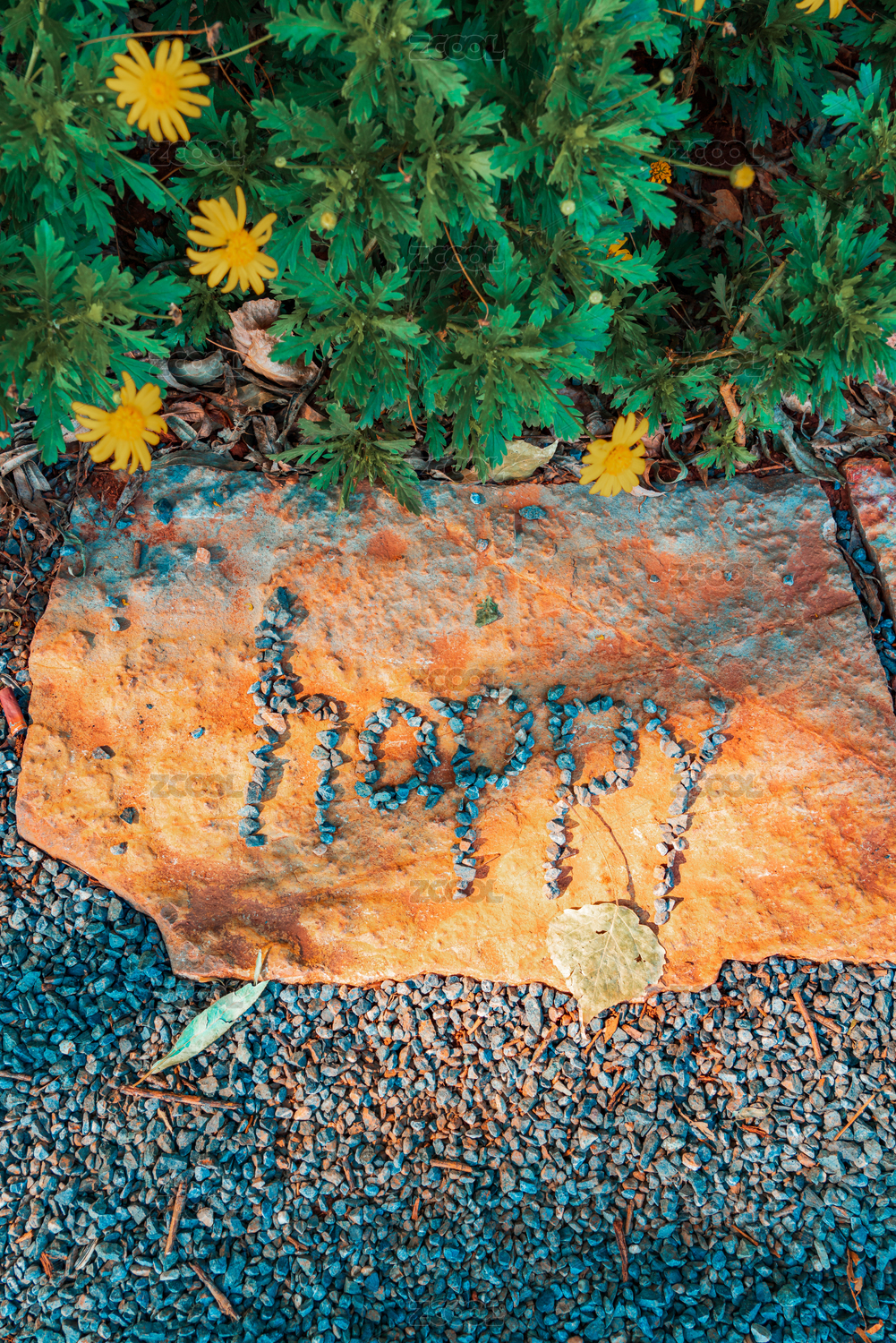 在黄色石块上用碎石拼成的happy(快乐)图案