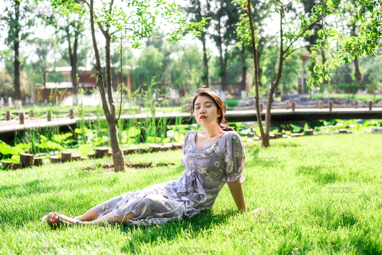 美丽优雅的亚洲女性坐在草地上，夏日午后的花园里，中国古典花园