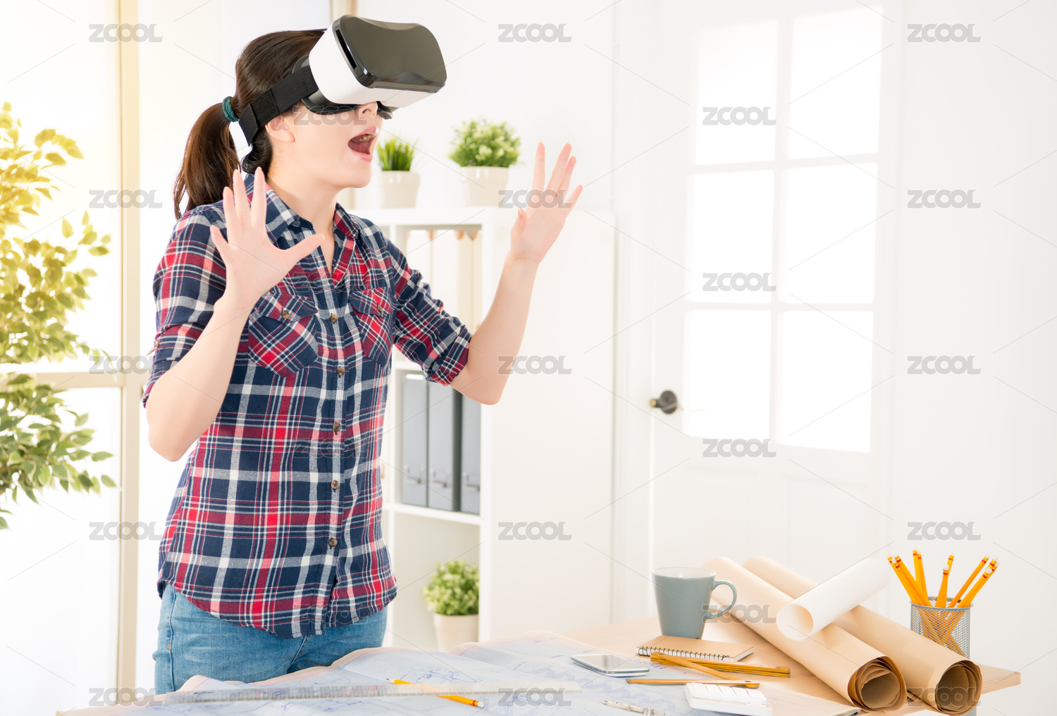 中国的亚洲女孩室内设计师是在三维可视化，而在创意办公工作室的办公桌在惊讶的VR设备，因为立体效果。职业和职务侵占的概念。