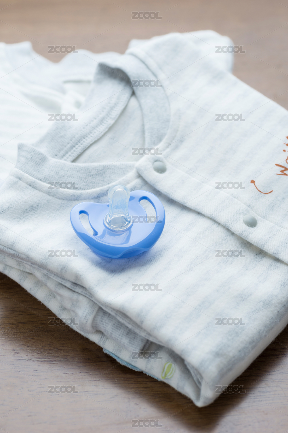 整齐折叠的婴幼儿连体服装和安抚奶嘴